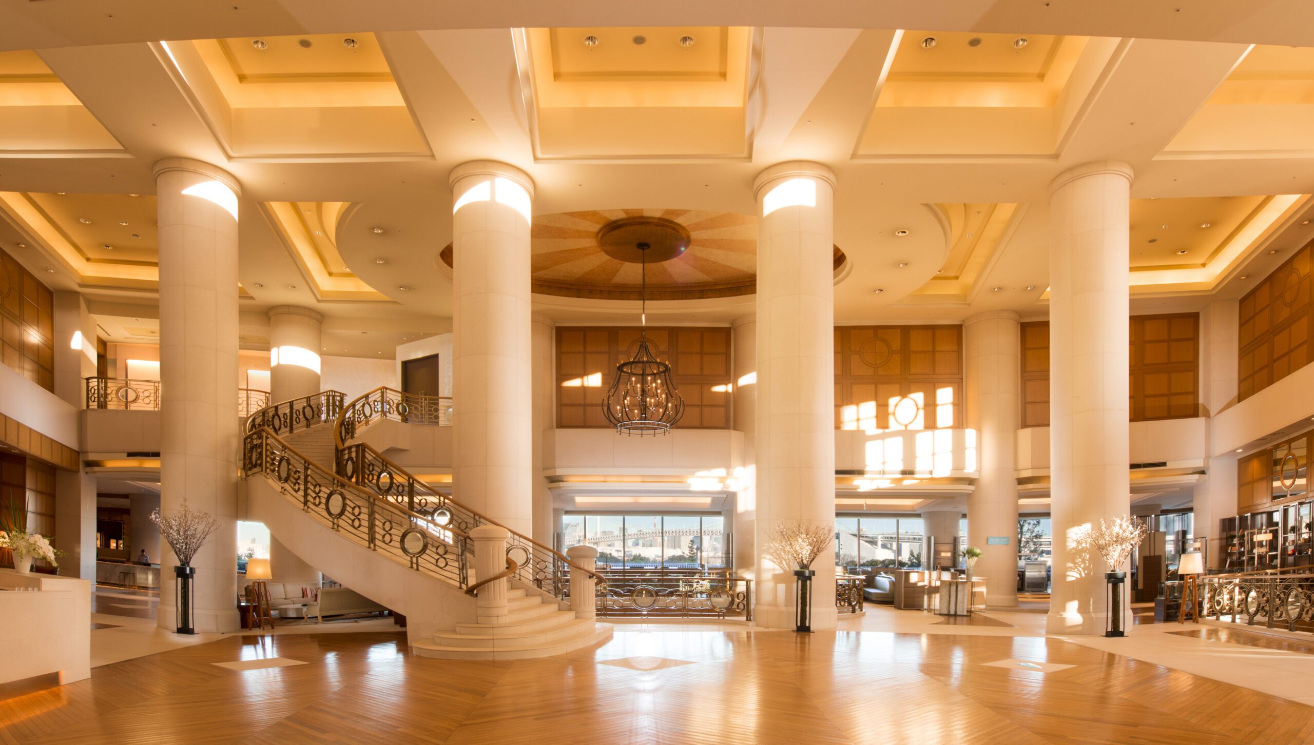 a grand, light-filled hotel lobby with multiple two-story pillars
