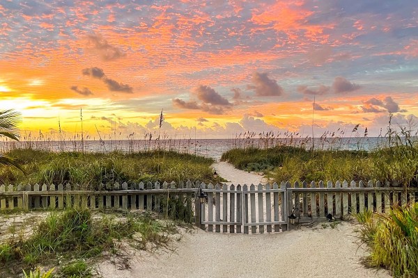 a path through grass-covered dunes to the water