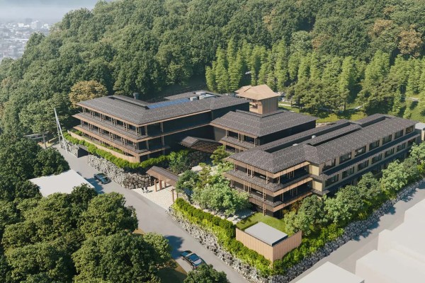 Aerial view of a four-story hotel surrounded by green trees