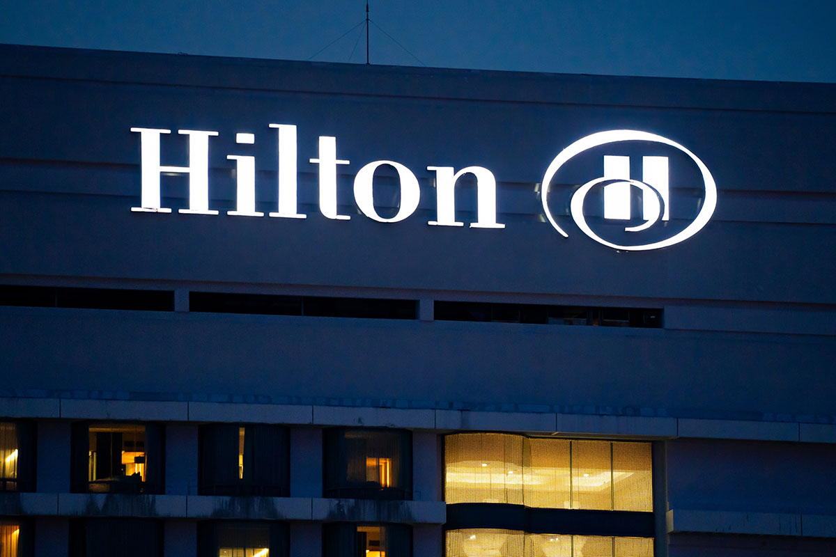 view of the top floors of hotel with a Hilton logo lighting the night