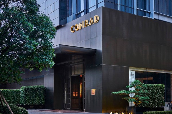 Exterior of a hotel with a large window and black marble walls.