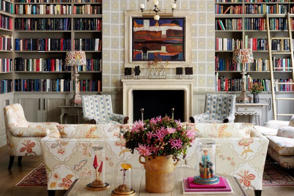 a colorful sitting room with bookcases and flowers