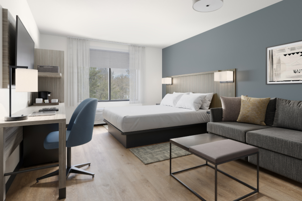 view of a hotel room with a couch and a desk in the foreground.