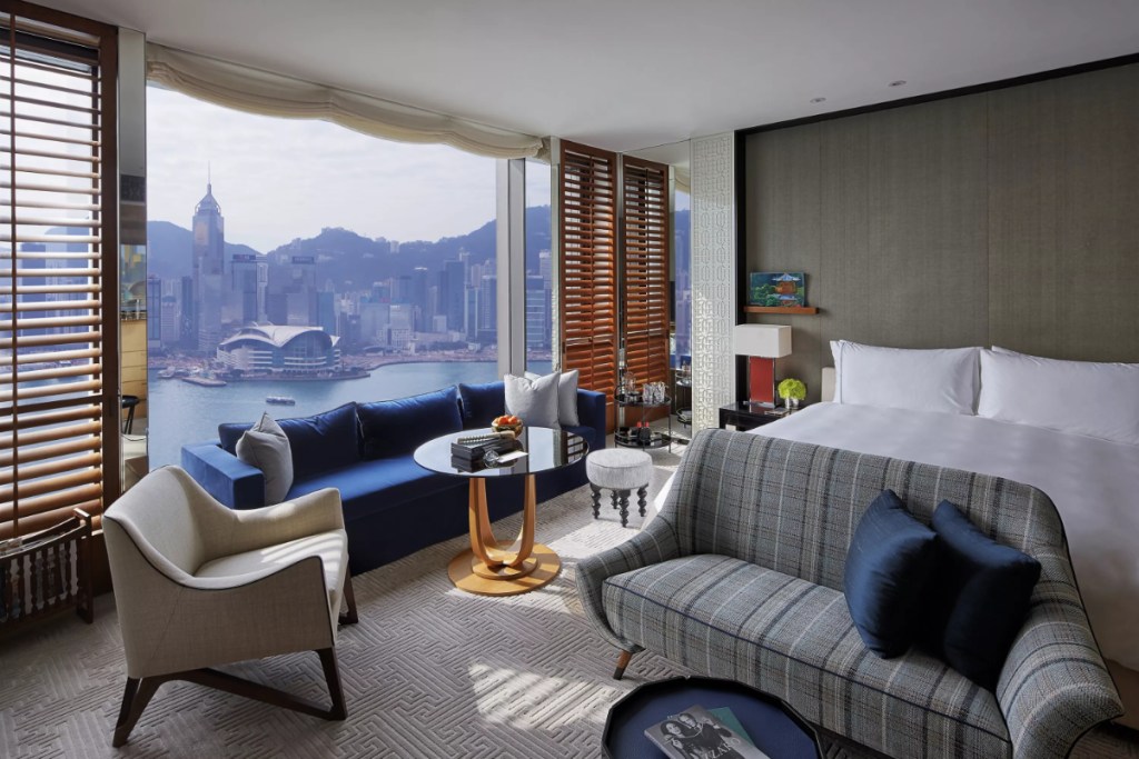 View of a luxurious hotel room at the Rosewood, Hong Kong, with a harbor view and a king bed.