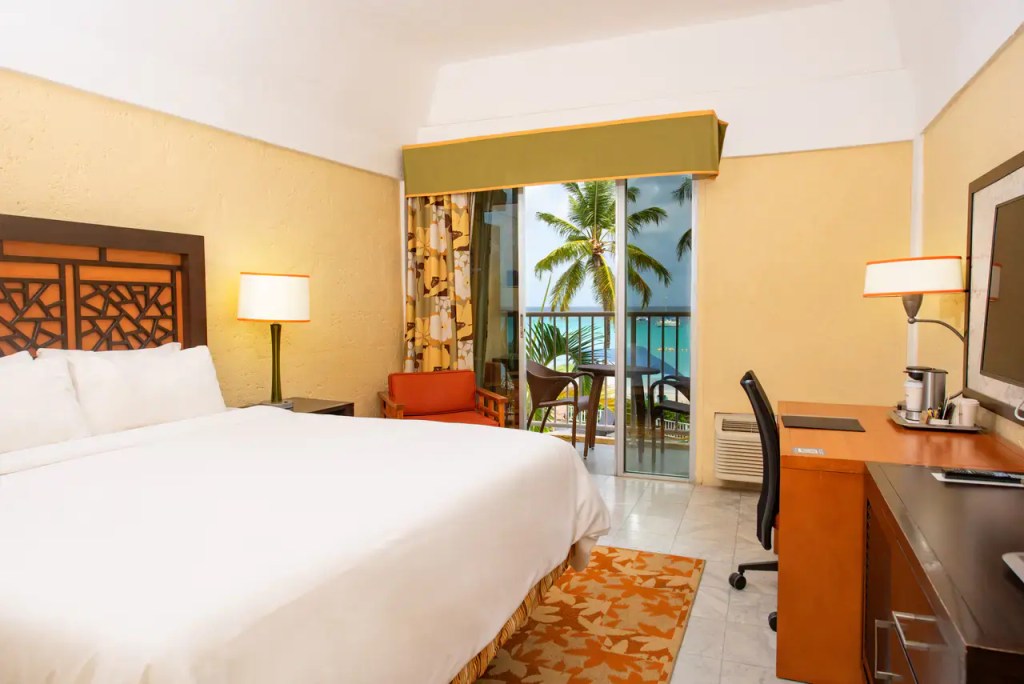 a guest room with a palm tree out the window at the Radisson Aquatica Resort Barbados