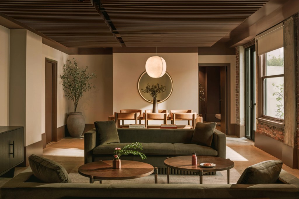 Image of a hotel guest room at the brand Sonder, which has now gone defunct. Lots of warm earth tones and distinctive looking furniture.