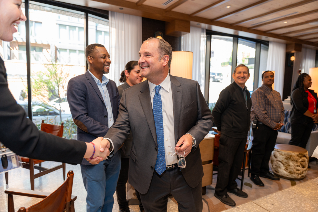 Image of a hotel executive greeting people while wearing a business suit.