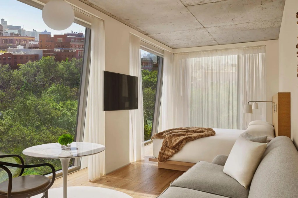 a sunlight hotel suite with window looking at trees in new york city