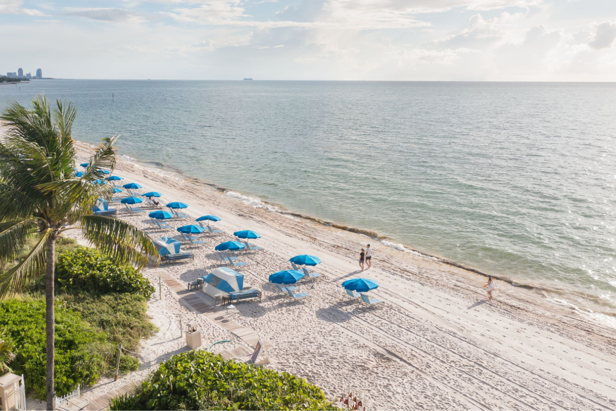 image of a beachfront with beach chairs on a sunny day in front of the Ritz-Carlton Key Biscayne Hotel