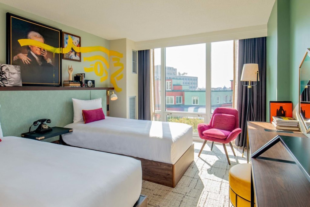 Image inside a hotel guest room in the DuPont Circle neighborhood of Washington, D.C. looking out. It's a plain room with two beds, and there's sunshine streaming through the window.