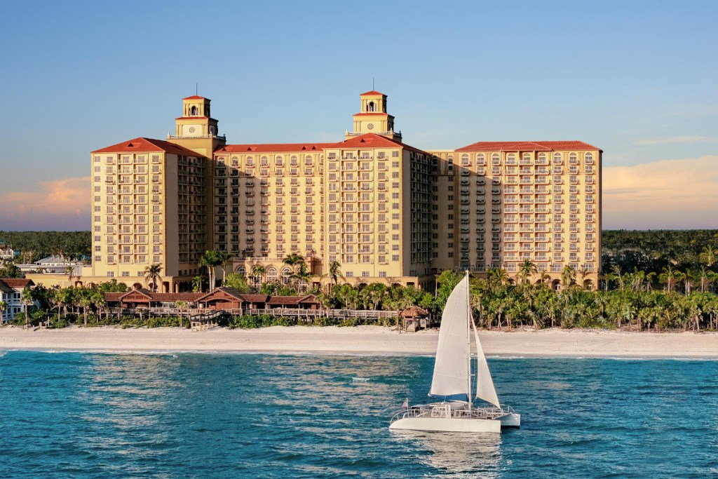 image of a luxury resort in florida bathed in sunlight from the outside with a sailboat passing by in front of it
